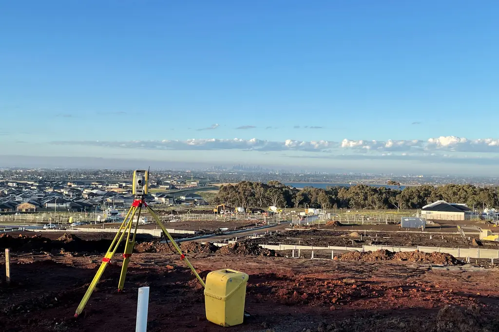 Konut inşaatı sahasında ölçüm için kurulmuş total station ve arkada şehir silueti